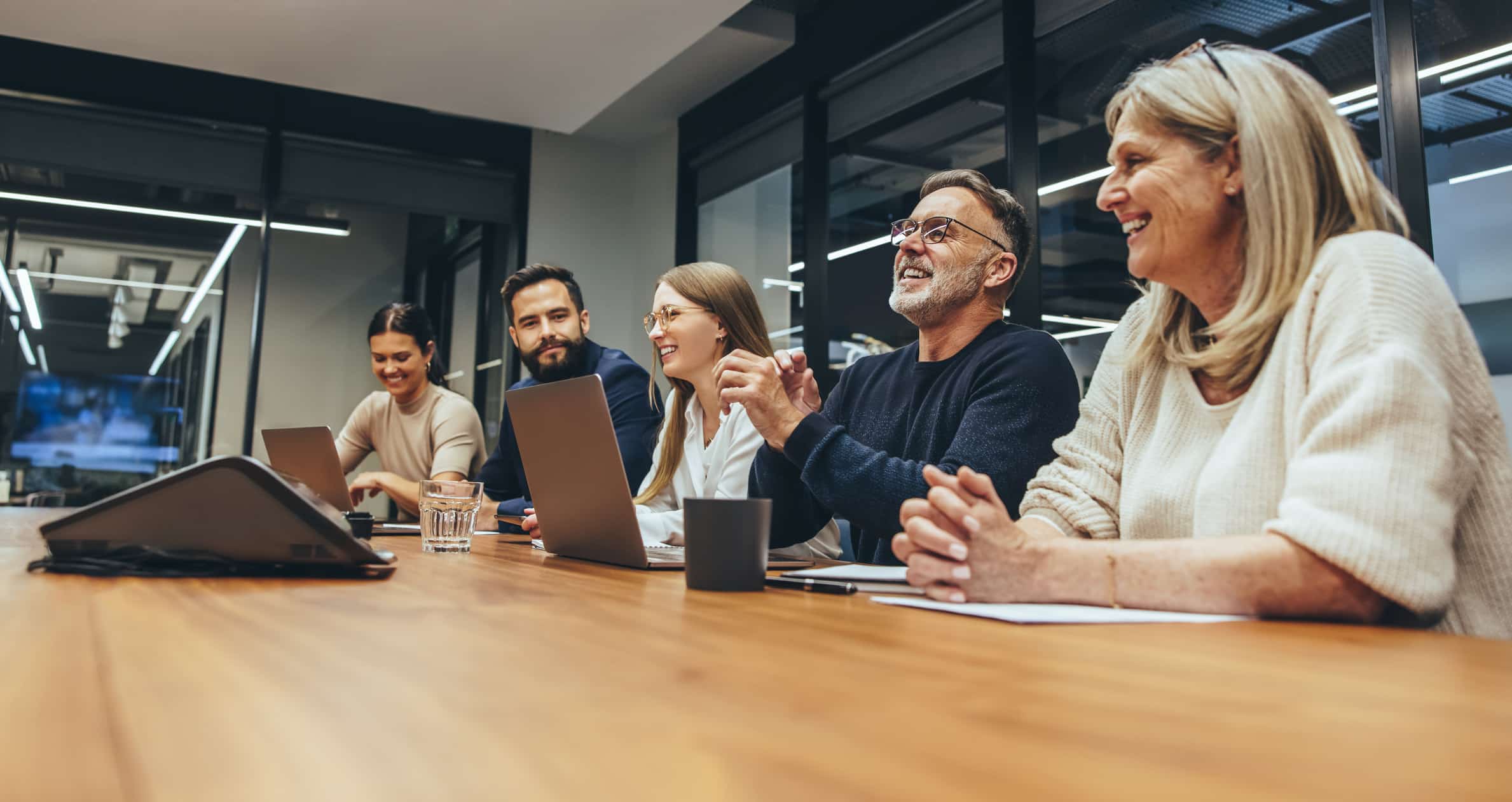 Cheerful business professionals laughing during a briefing. Group of happy businesspeople enjoying working together in a modern workplace. Team of diverse colleagues having a meeting in a boardroom.